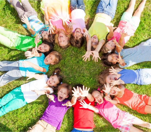 a circle of happy kids lying on the ground together